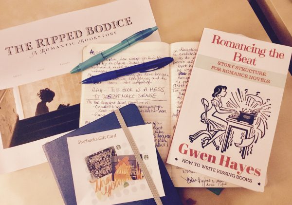 Photo of giveaway prizes: notebook, pens, Starbucks and The Ripped Bodice gift cards, Romancing the Beat book